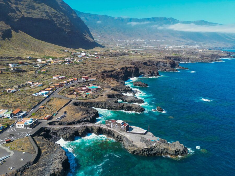 Aerial view of El Hierro volcanic cliffs, turquoise sea, rocky coastline, coastal village.