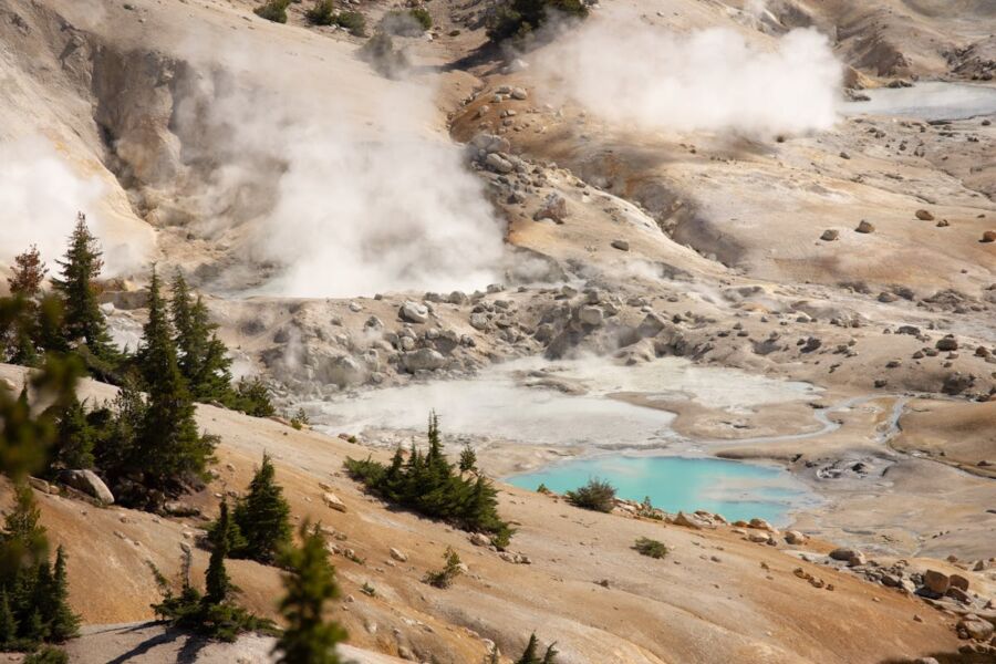 Geothermal landscape with vibrant hot spring, steam, and colorful mineral-rich rocks.
