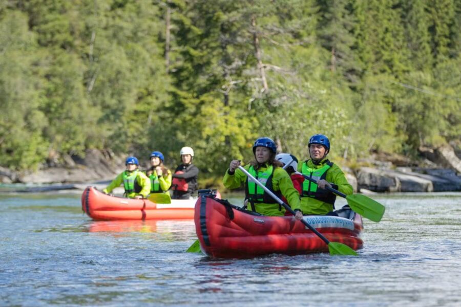 Three people kayaking on the Voss river during a combo tour featuring SUP, canoe, mountain biking, and sea kayaking.
