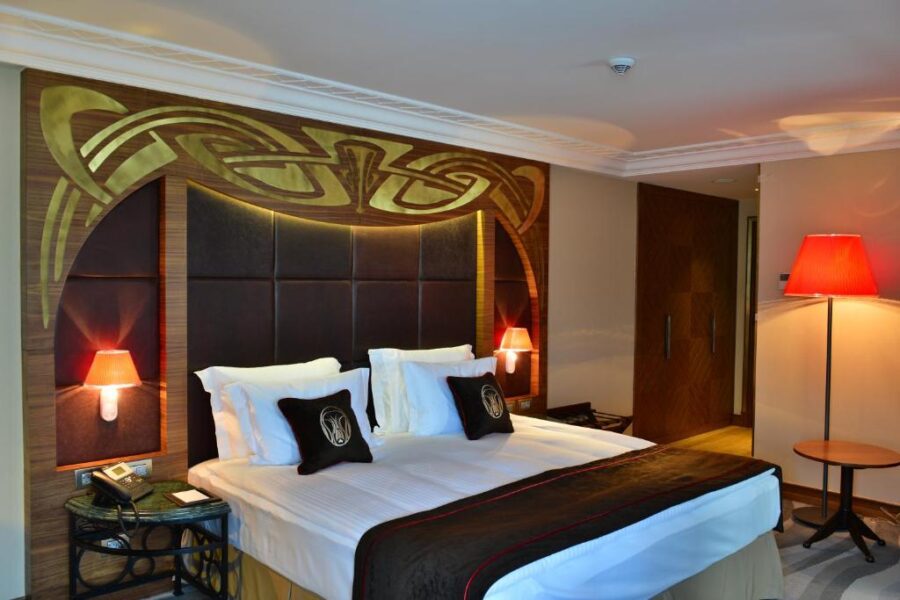 Spacious hotel room at Warwick Ankara featuring a large bed with an elegant headboard.