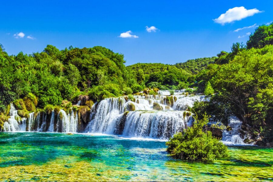 Cascading waterfalls at Krka National Park, surrounded by lush greenery and turquoise waters.