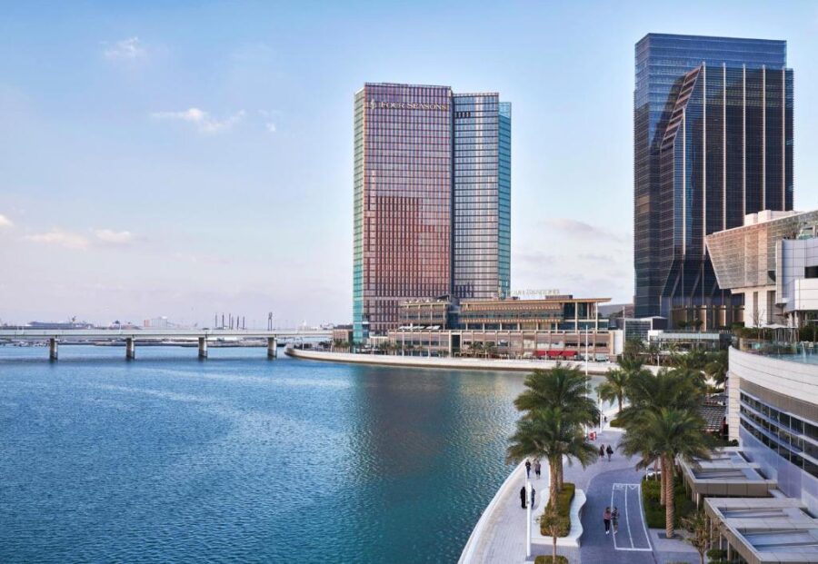 Luxury Four Seasons Abu Dhabi waterfront hotel, modern skyscrapers, palm-lined promenade, and serene marina.