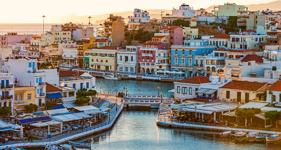 Charming Mediterranean coastal town at sunset with colorful buildings and tranquil harbor.