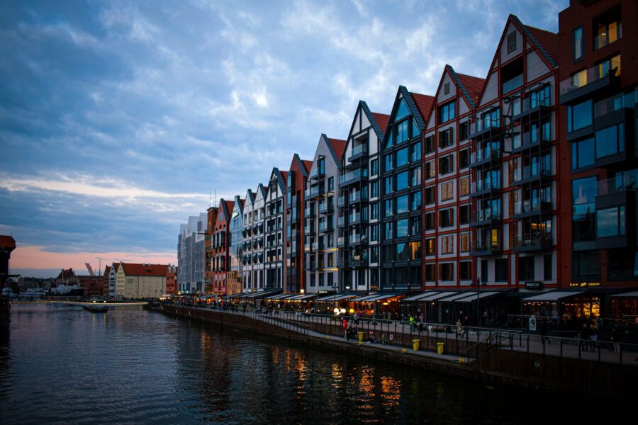Modern riverfront buildings at dusk, vibrant architecture, scenic waterfront, Gdańsk, Poland.