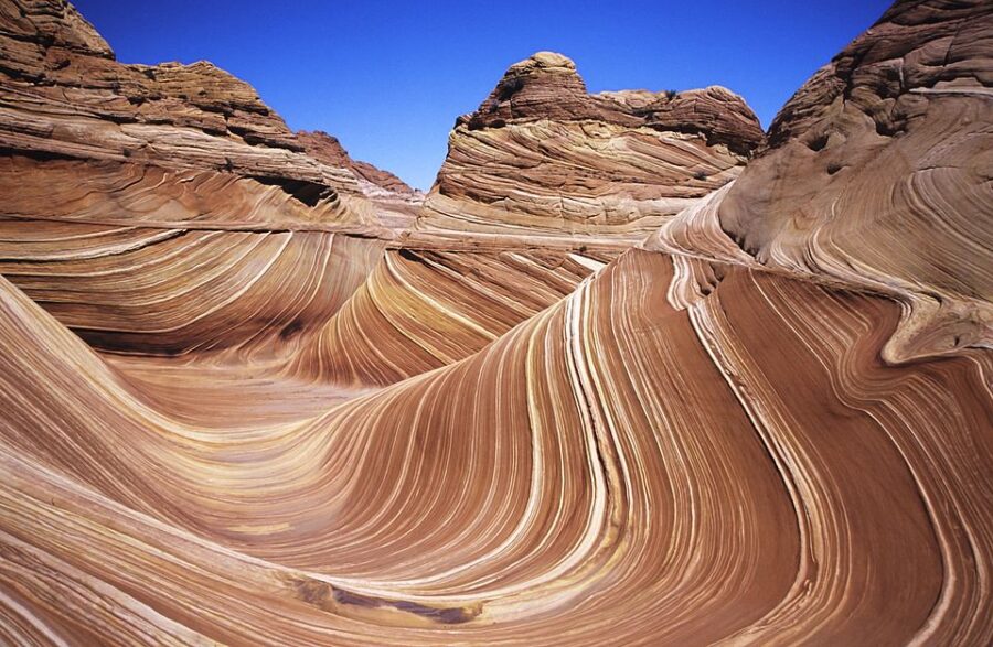 The Wave in Arizona: stunning swirls of red and orange rock formations under clear blue sky.