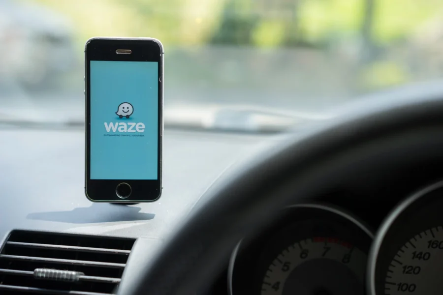Waze navigation app on smartphone mounted on car dashboard, GPS ready.