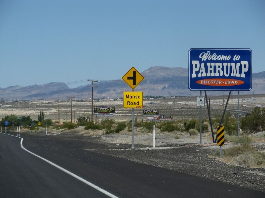 Welcome to Pahrump sign with desert landscape and road infrastructure.