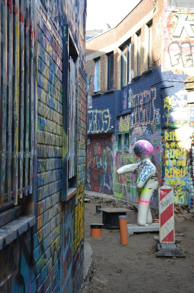 White statue of a woman is featured amidst vibrant graffiti on Werregarenstraat in Gent.

