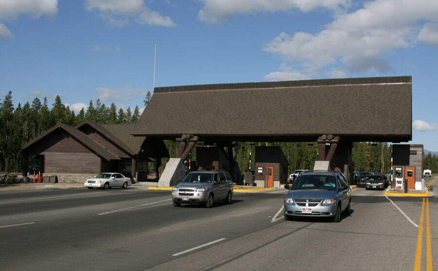 Large wooden structure at the West Entrance of Yellowstone National Park, showcasing rustic architecture and natural surroundings.