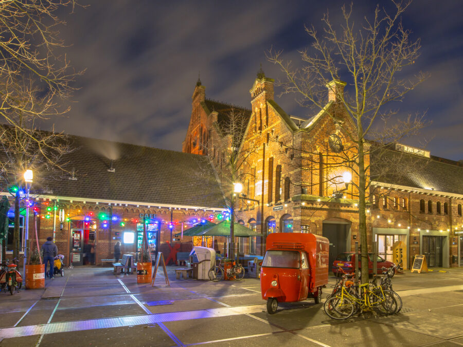 Nighttime city scene with a red truck and a building, highlighting the Westerpark Food Forest in Amsterdam.