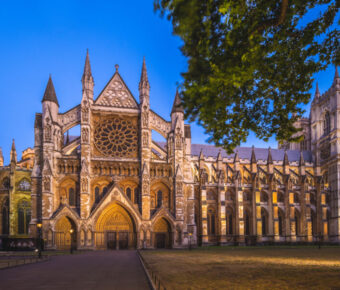 Westminster Abbey illuminated at night, showcasing its stunning Gothic architecture against a dark sky in London, England