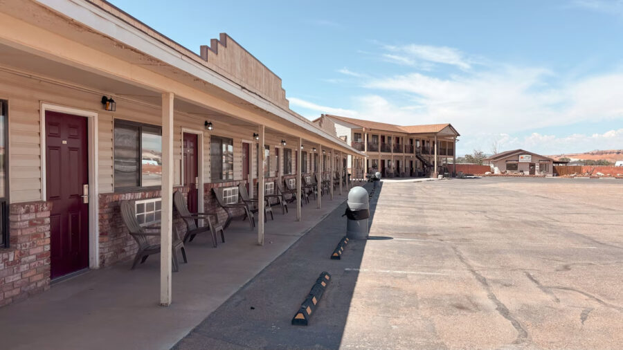Exterior view of Whispering Sands Motel featuring a parking lot and a few chairs for guests to relax.