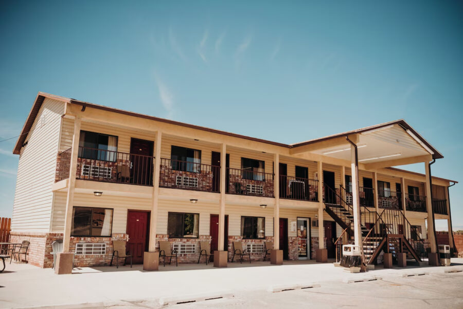 Exterior view of Whispering Sands Motel in Hanksville, Utah, featuring a parking lot and welcoming entrance.