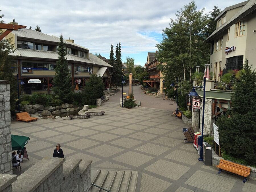 Crowds of people stroll along a lively street in Whistler, British Columbia, showcasing the town's bustling activity.