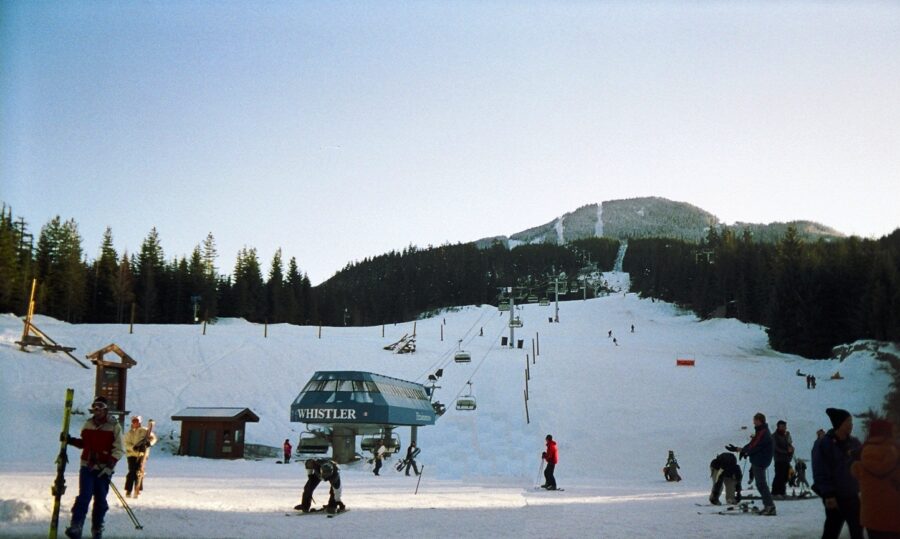 Skiers and snowboarders gather on the slopes at Whistler Creekside, showcasing a vibrant winter sports scene.