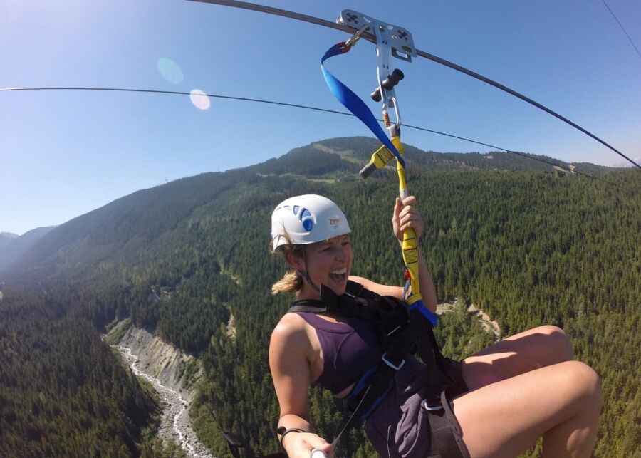 Woman glides on a zipline through the mountains during the Whistler Sasquatch Zipline Experience.