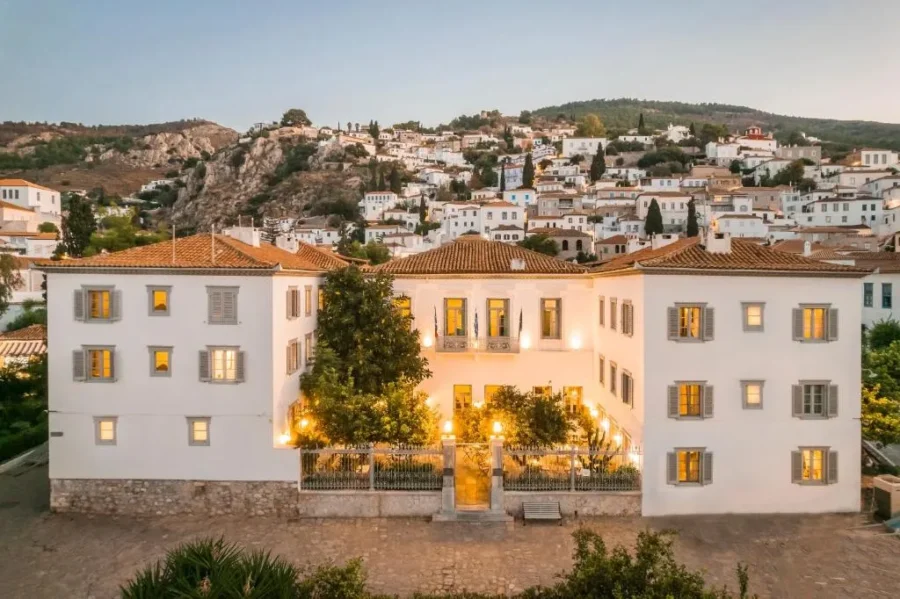 Hydra boutique hotel: white Mediterranean villa at dusk with illuminated courtyard.