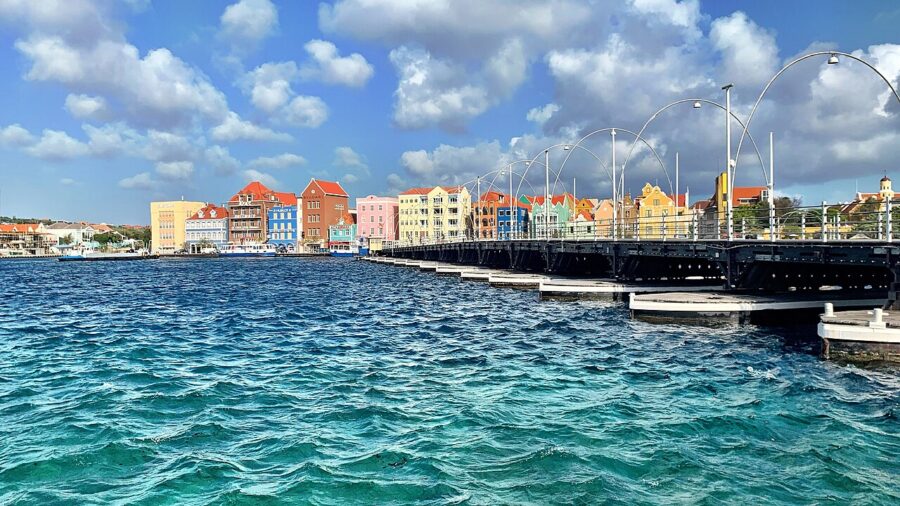 Bridge spans a pier over water, with charming buildings lining the shore in Willemstad, the capital of Curaçao.

