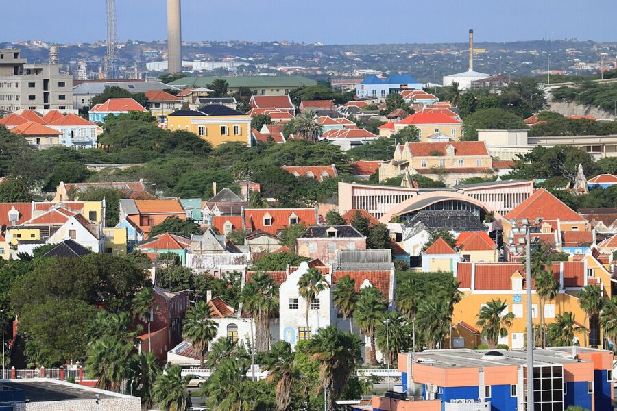 Aerial view of Willemstad, Curacao, featuring a prominent clock tower and a large clock in the cityscape.
