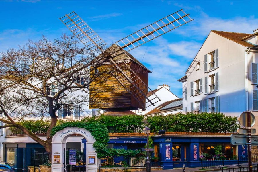 Moulin de la Galette windmill above Paris street café with timber sails.