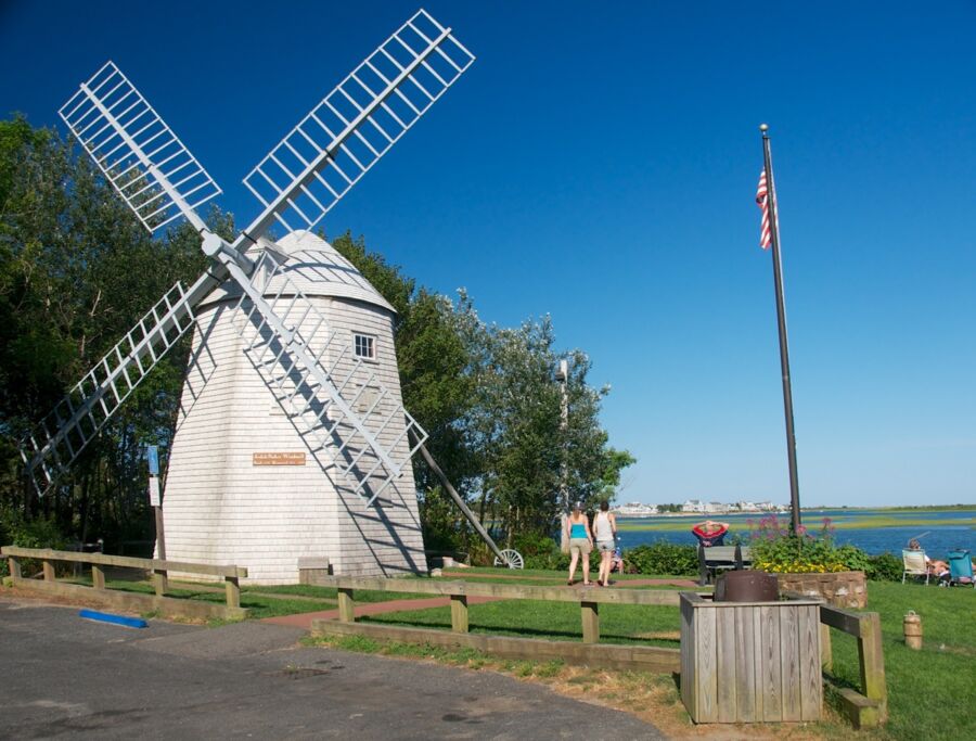 Classic windmill with American flag by coast in summer, evoking nostalgia and heritage.