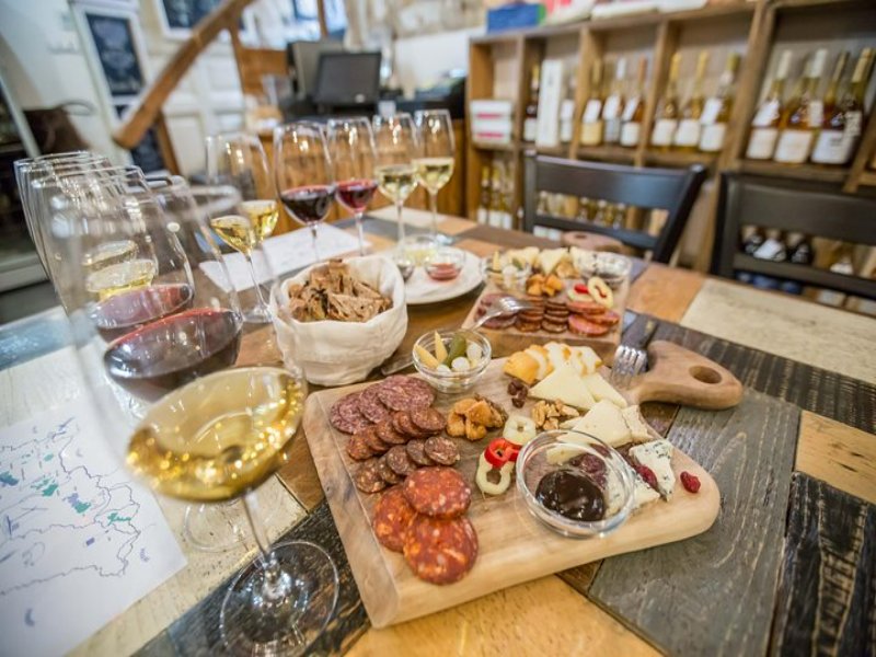 Wine tasting with charcuterie board and cheeses, assorted wines and glasses in boutique tasting room.