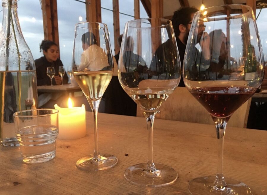 Romantic restaurant wine tasting with candlelight, water glasses, wooden table, and evening diners.