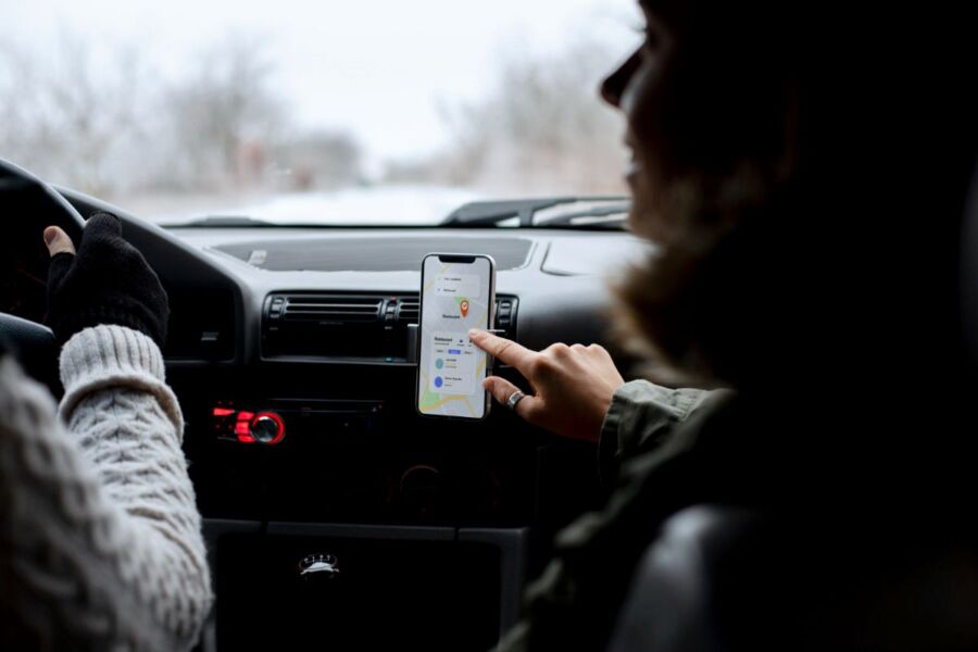 Winter drive with navigation app, two people, cozy attire, and vibrant dashboard elements.