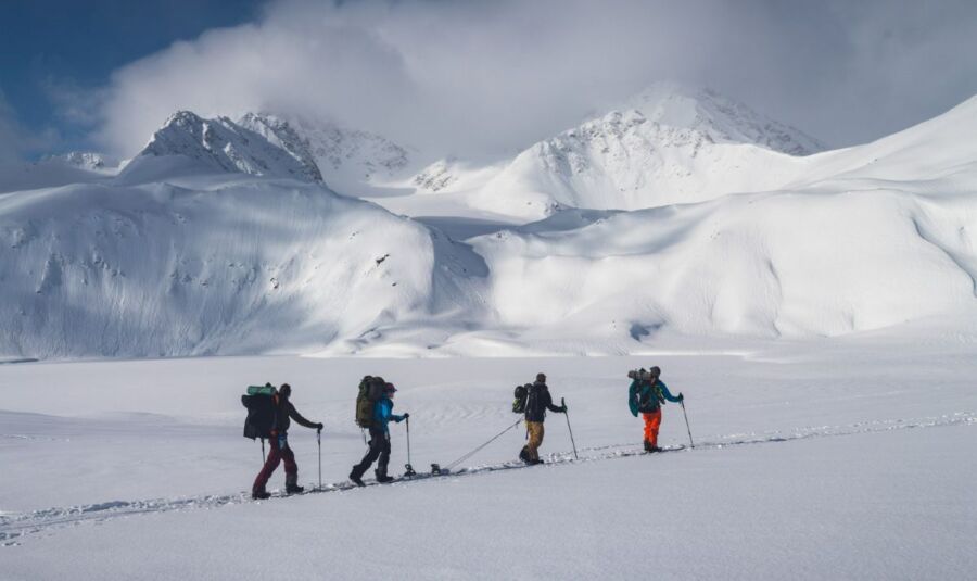 Skiers traverse snowy mountain range under clear sky, embracing winter adventure and natural beauty.