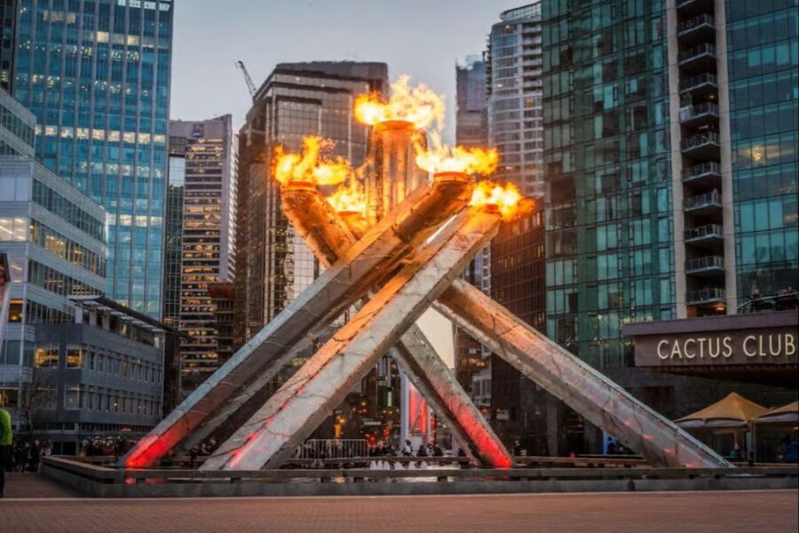 The Olympic flame is lit in front of a tall building during the Winter Olympics in Vancouver.
