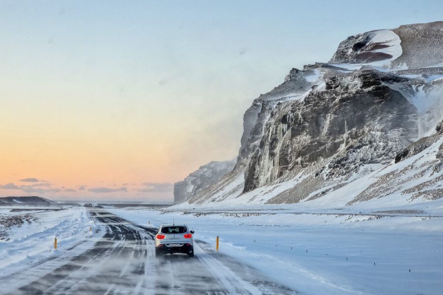 Winter road trip through snowy cliffs at dawn, showcasing solitude and adventure.