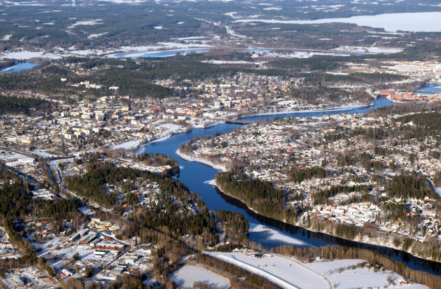 Aerial view of snowy Kouvola, Finland, with river, pine trees, and winter landscape.