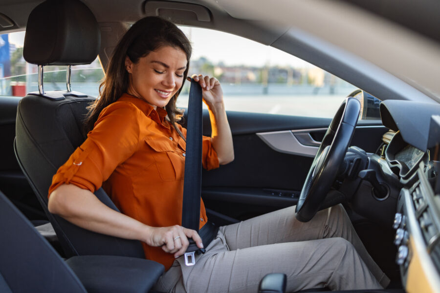 Young woman in comfortable attire fastening her seat belt while seated in a car