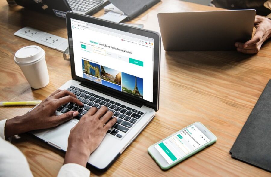 Modern workspace with laptop and smartphone displaying travel booking websites.