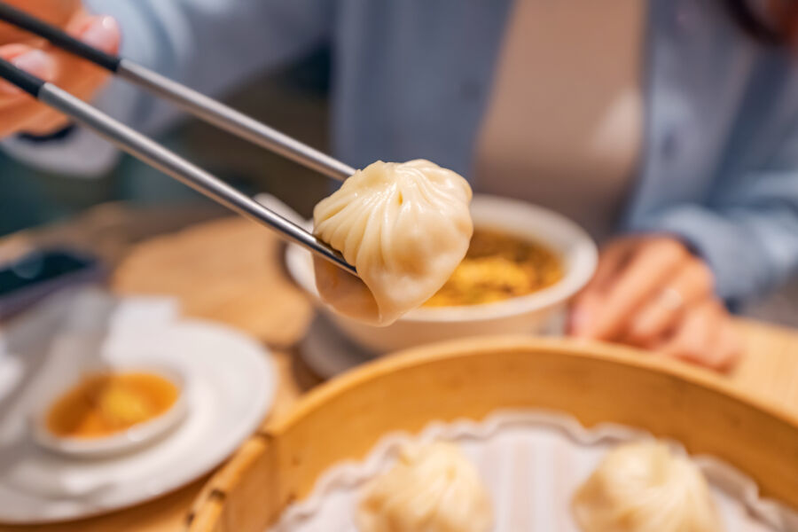 Metal chopsticks holding a xiaolongbao dumpling