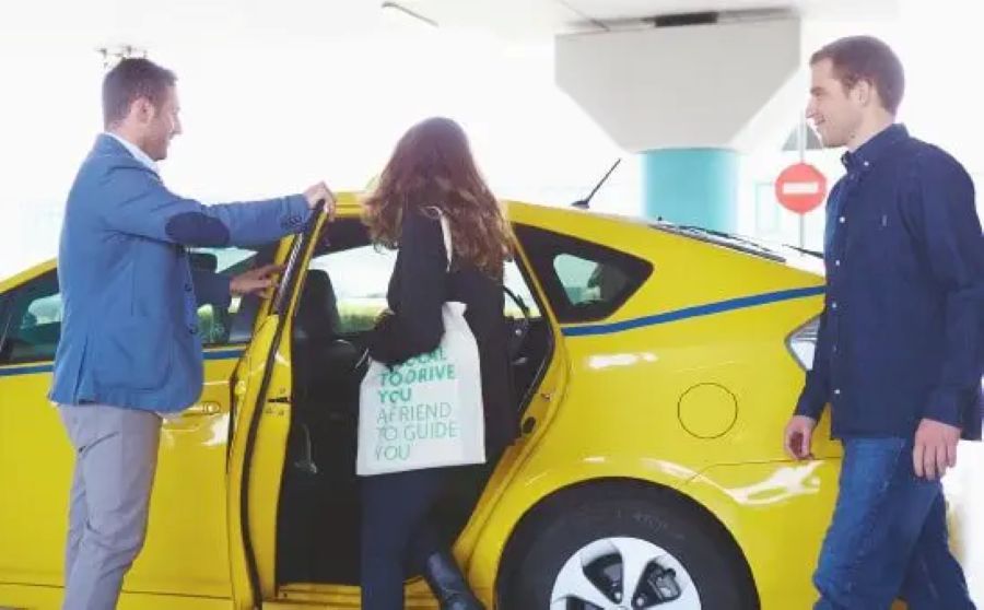 Yellow hatchback with open rear door and passengers at Chania airport pickup.