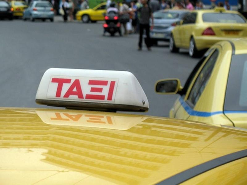 Yellow taxi roof sign reflected on hood, blurred city street background.