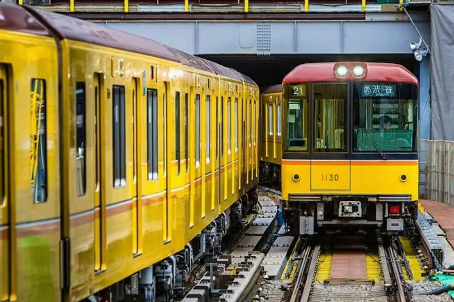 Yellow commuter trains 1130 on adjacent urban rail tracks in maintenance corridor.