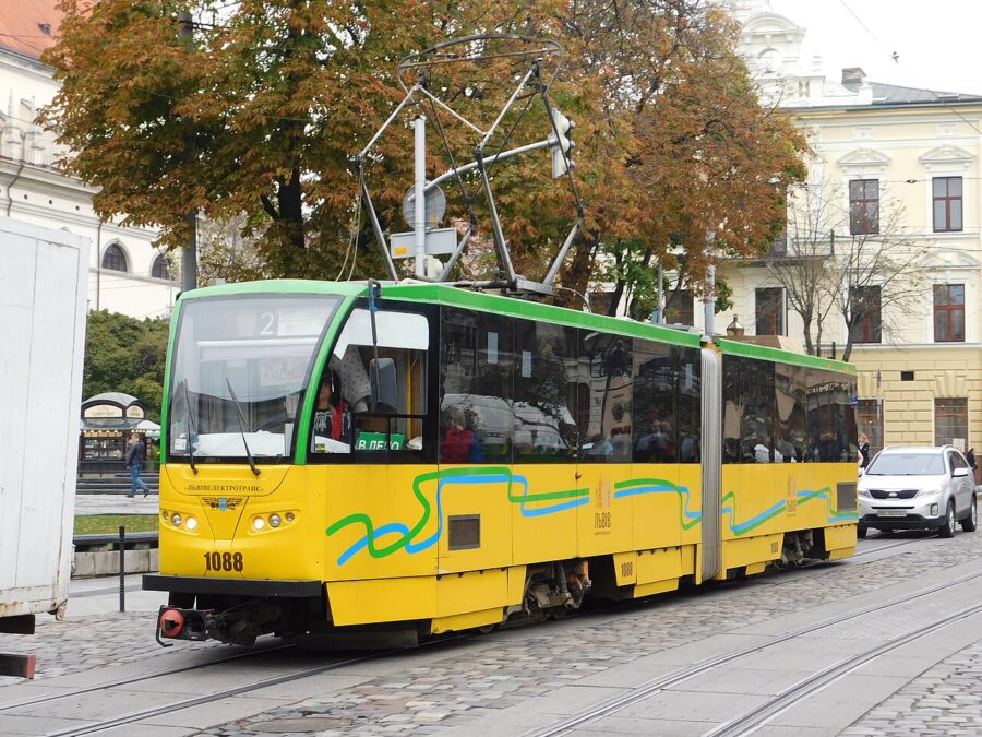 Yellow and green tram on cobblestone street in autumn urban scene, Lviv, Europe.