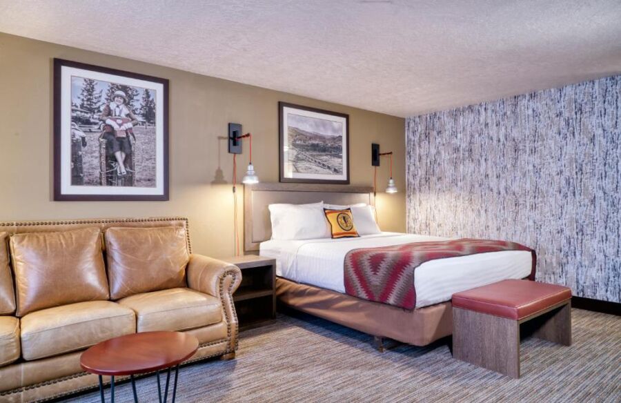Interior of a Yellowstone Park hotel room showcasing a cozy couch, a bed, and a chair for guests' comfort.