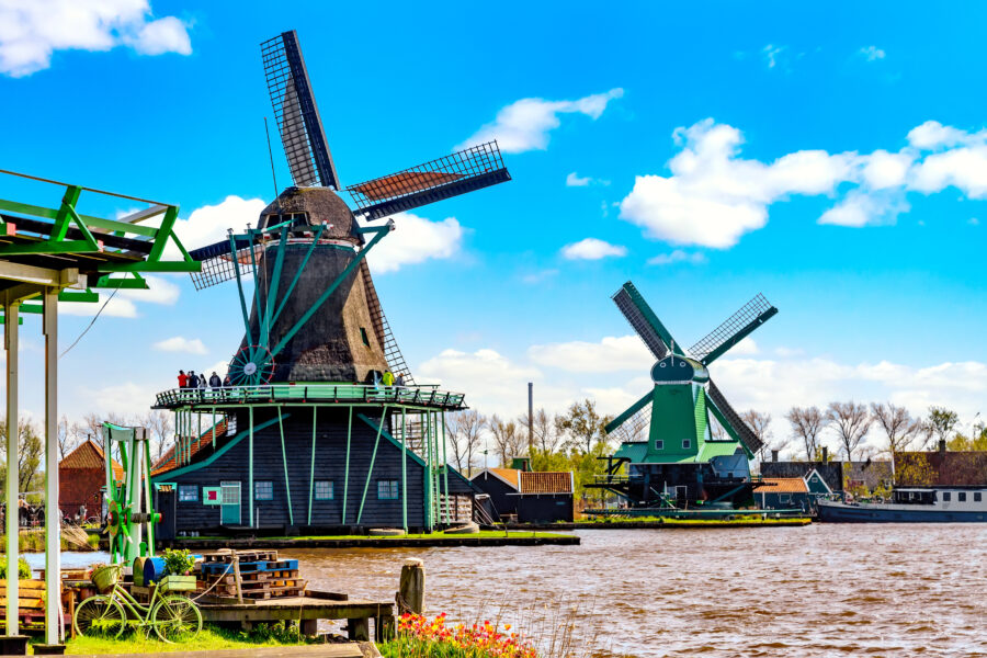 Iconic Dutch landscape featuring windmills and a vintage bicycle in Zaanse Schans, a popular tourist spot in Holland.