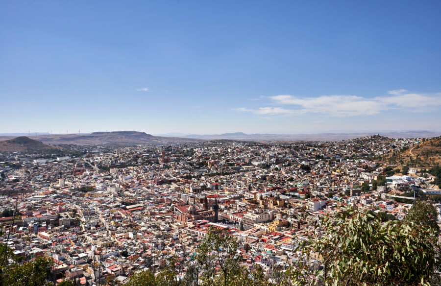 Aerial view of Zacatecas, Mexico, featuring its vibrant cityscape and rugged terrain, with sunlight illuminating the scene