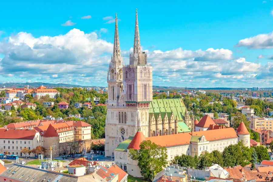 Aerial view of Zagreb Cathedral with surrounding cityscape and lush greenery.