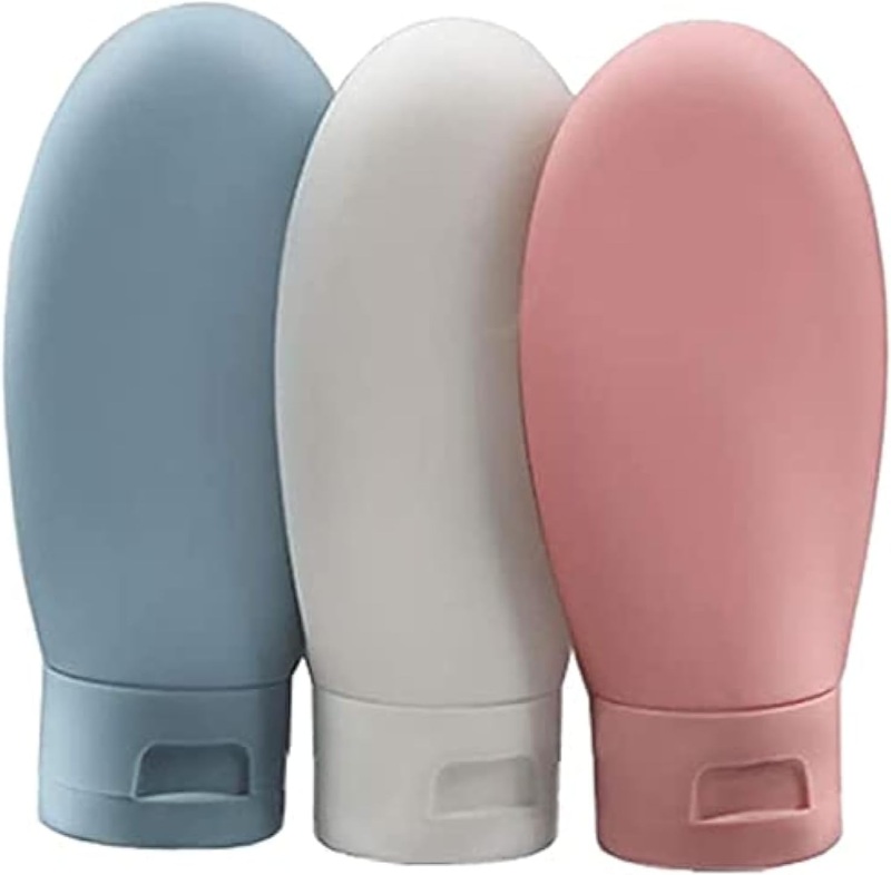 Three colorful ZALUJMUS travel soap bottles in blue, green, and pink arranged together on a white background.