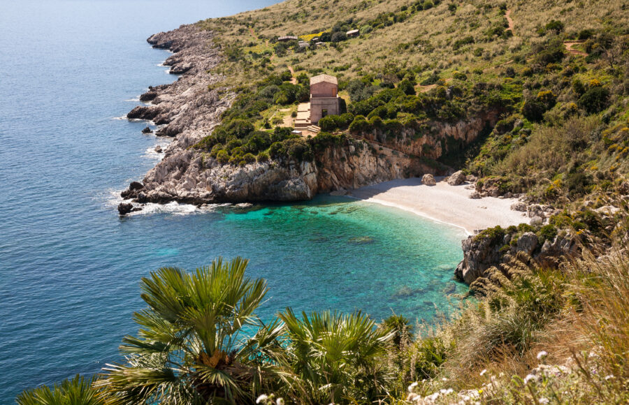 Scenic view of Zingaro Nature Reserve in Sicily, showcasing rugged cliffs, lush greenery, and the sparkling Mediterranean Sea.