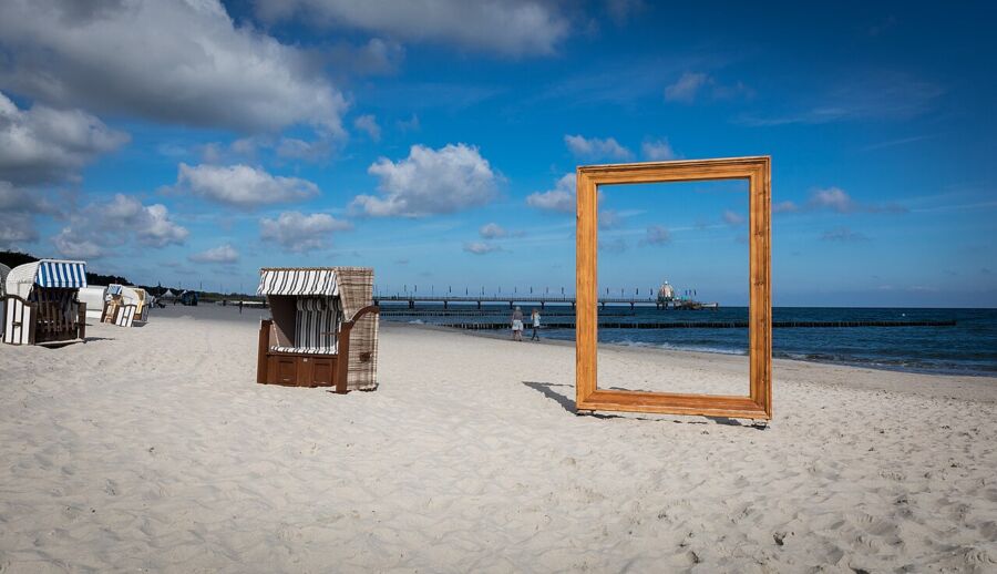 Wooden frame and a chair on the beach, showcasing the scenic panorama of Zingst, Germany.