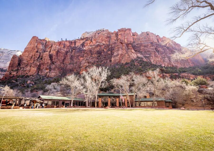 Zion National Park Lodge nestled among towering red rock formations in Utah, surrounded by lush greenery and scenic views.
