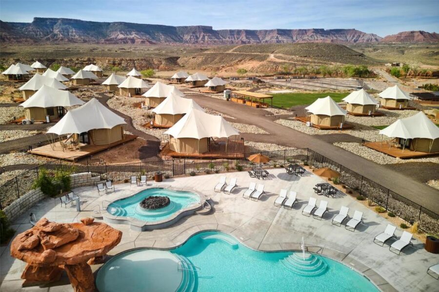The pool area of Zion Wildflower Resort, with tents nearby and a stunning mountain view in the distance.