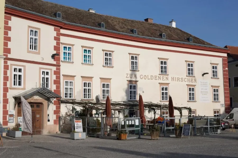 Zum Goldenen Hirschen restaurant exterior with outdoor terrace on cobblestone square.