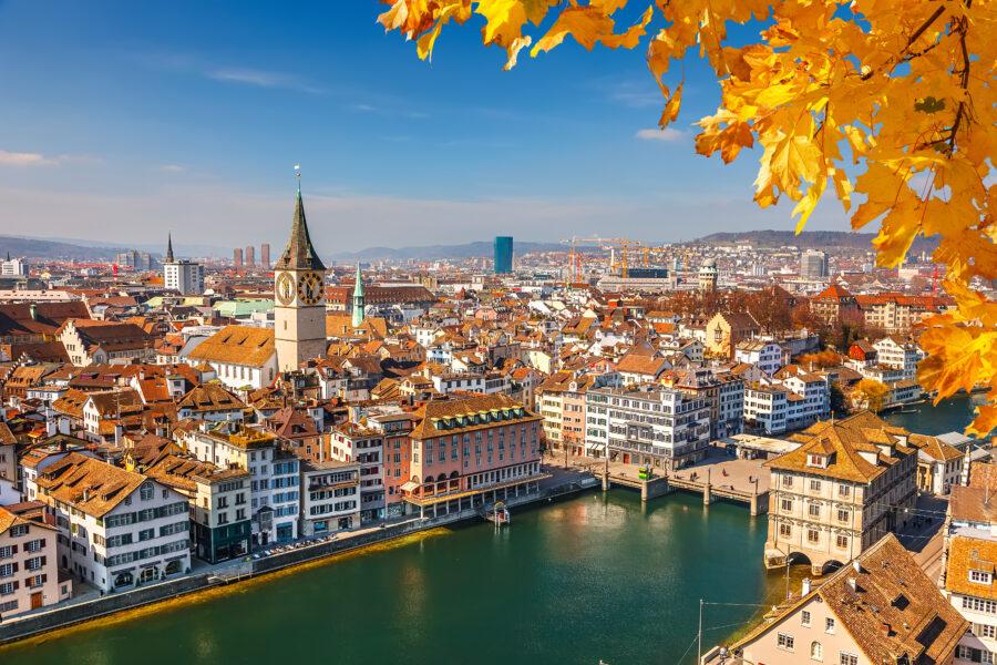 Sunny autumn day in downtown Zurich, showcasing vibrant fall foliage and bustling city life.
